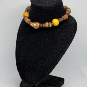 Brunt och gult armband med dödskalle - Unikt armband med bruna och gula pärlor samt en cool dödskalle. Perfekt för att ge din outfit en edgy touch. Passar bra till både vardag och speciella tillfällen.