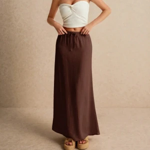 Brun långkjol med knytband - Snygg brun långkjol med knytband i midjan. Perfekt för en avslappnad stil. Kjolen har en enkel och elegant design som passar till många olika tillfällen.