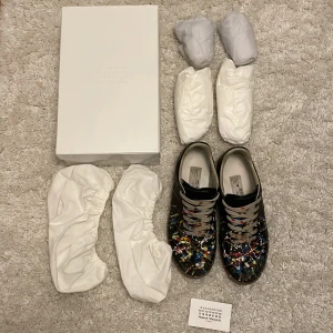 svarta gats med paint splatter från Maison Margiela - säljer ett par svarta Mason Margeila i läder med paint splatter i storleken 41! Fint skick endast lite slitet på baksidan av höger sko! box,skopapper,skoskydd i tyg och ett kort tillkommer! 