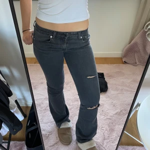 Svarta jeans med slitningar - Snygga svarta jeans med slitningar på knäna. De har en lågmidjad passform och raka ben. Perfekta för en avslappnad stil.