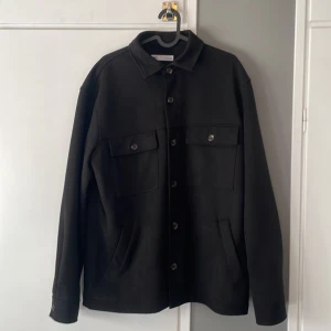Svart overshirt från ZARA - Snygg svart overshirt med knappar och två bröstfickor. Knappt använd pga för stor.                                                      Storlek M passar L också. Nypris: 559kr. Skick 9/10, inga defekter. Hör av er vid frågor! 