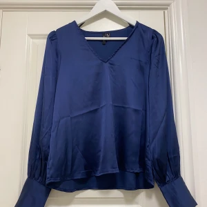 V-ringad blus  - V-ringad blus från Vero Moda. Knapp detaljer på ärmarna.