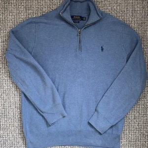 Blå tröja med dragkedja från Ralph Lauren - Säljer en stilren blå tröja från Ralph Lauren i mjuk pima bomull. Tröjan har en halv dragkedja och det klassiska logotypbroderiet på bröstet. Perfekt för en avslappnad men ändå snygg look.