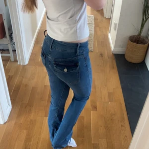 Blå bootcut jeans - Snygga blå bootcut jeans med låg midja. De har klassiska femficksdetaljer och en stilren design. Perfekta för en avslappnad look. Storlek XXS aldrig använda köptes för 699kr