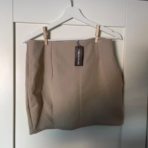 Oanvänd Beige kjol från PrettyLittleThing - Snygg beige kjol från PrettyLittleThing i en klassisk och stilren design.  Prislapp kvar