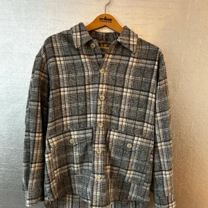 Grå beige rutig overshirt - Snygg grå rutig overshirt från JUNKYARD. Jackan har långa ärmar och knappar framtill. Perfekt nu till höst och vår. Overshirten är oanvänd och har superskönt material. Passar M/ S