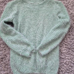 Mintgrön fluffig tröja - Säljer en supermjuk och fluffig mintgrön tröja. Perfekt för kyliga dagar med sin mysiga känsla. Tröjan har långa ärmar och en rund halsringning. Passar perfekt för en avslappnad stil. Från vero moda utan lapp. Går ej att förhandla, priset är fast