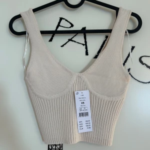 Beige ribbad linnetopp från Gina Tricot - Snygg beige ribbad linnetopp med breda axelband och en stilren design från Gina Tricot i storlek XS. Passar bra till både jeans och kjol. Köptes för 199 kr och är aldrig använd.