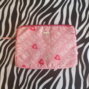 Rosa dataväska från Victoria's Secret - Säljer en söt rosa dataväska från Victoria's Secret med hjärtmönster och logotyp i guld. Aldrig använt men har haft den i garderoben as länge så det är därför det finns små anmärkningar på den (sista bilden). Man kan lägga en surfplatta eller en dator eller egentligen vad du själv vill helt enkelt. Pris kan diskuteras vid snabb köp.💗