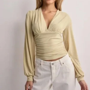 Beige omlottopp - Helt slutsåld❤️Snygg beige omlottopp med långa ärmar och v-ringad design. Toppen har en smickrande passform med rynkade detaljer som ger en elegant look. Perfekt för att klä upp eller ner beroende på tillfälle.