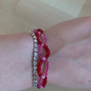 Färgglatt pärlarmband - Säljer ett färgglatt armband med pärlor i rött och rosa. Armbandet har en unik design med flera rader av pärlor och ett smidigt lås. Perfekt för att ge en färgklick till din outfit! Kostar 15kr