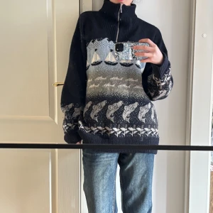 Mönstrad stickad tröja med dragkedja - Säljer en unik stickad tröja med dragkedja och hög krage. Tröjan har ett maritimt mönster med segelbåtar och vågor i blått och grått. Perfekt för kyliga dagar.