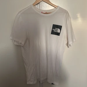 Vit t-shirt från The North Face - Säljer en vit t-shirt från The North Face med en svart logga på bröstet. T-shirten har en klassisk passform och är kortärmad. Perfekt för en avslappnad stil. Tröjan behöver strykas annars väldigt bra skick 