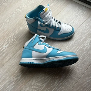 Nike Dunk Blå/turkos & Vit  - Snygga Nike Dunk sneakers i en fräsch kombination av blått/turkos och vitt. Skorna har en hög modell. Stroleken är 44. Låda saknas. 
