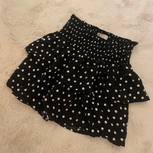 Prickig Kjol - Hejj! Säljer denna supersöta svart-vita prickiga kjolen med volang som verkligen är perfekt till sommaren.😍Kjolen är knappast använd och har därav inga defekter. Skulle påstå att kjolen passar dig som har storlek XXS-S. Om ni skulle ha några frågor är det bara att höra av er, annars går det superbra att trycka på ”köp”.
