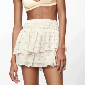 Volangkjol zara - Charmig vit kortkjol från Creamie med glittriga guldprickar och volangdetaljer. Kjolen har en elastisk midja för en bekväm passform. Perfekt för att lägga till lite glamour till din outfit!