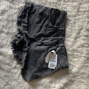 Svarta jeansshorts från Stradivarius - Snygga svarta jeansshorts från Stradivarius med fransiga kanter. Perfekta för en avslappnad stil. Passar perfekt till sommarens alla äventyr!
