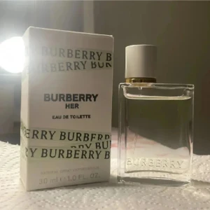 Burberry Her Eau de Toilette 30ml - Burberry Her Eau de Toilette i en stilren, transparent glasflaska med vit och guldig kork. Flaskan rymmer 30 ml och kommer i en vit kartong med Burberry-logga. Doften är fräsch och modern, perfekt för dig som gillar eleganta och trendiga parfymer.