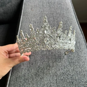 Glittrande silverfärgad tiara - Superfin tiara i silverfärg med massor av gnistrande stenar och detaljerad design. Kronformad med höga spetsar och glittrande kristaller som ger en riktigt lyxig och kunglig känsla. Perfekt för dig som vill sticka ut och känna dig som en drottning.