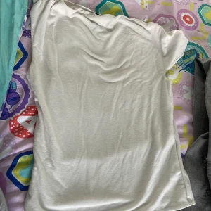 Vit omlott topp från H&M Divided XXS - Säljer en vit omlott topp från H&M Divided i storlek XXS. Toppen har en lätt draperad effekt vid halsen och är tillverkad i mjuk bomull. Perfekt för dig som gillar en enkel men ändå snygg look.