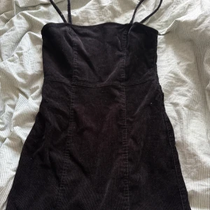 Svart manchesterklänning H&M Divided - Svart kort manchesterklänning från H&M Divided med smala axelband och en snygg dragkedja i ryggen. Klänningen har en figurnära passform🤍