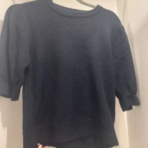 Mörkblå stickad tröja med puffärm från ginatricot  - Mysig mörkblå stickad tröja med rund halsringning och puffiga trekvartsärmar. Perfekt inför hösten och vintern! Använts en gång. Mjukt och fint material💙