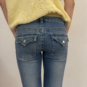 Blå bootcut jeans lågmidja - Snygga blå bootcut vintage jeans från Fishbone med låg midja och klassisk femficksdesign. Jeansen har coola ficklock med knapp bak. Så bra kvalitet!! Tillverkade i mjukt denim med stretch för skön passform. Low waist / lågmidjade / low rise / lågmidja