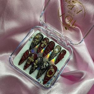 RoyalSin (S);Long Stiletto  - Snygga gelé långa press-on naglar i vinrött och svart med guldiga detaljer, kors och stenar. Naglarna har spetsig form och glittriga inslag, perfekta för dig som vill sticka ut. Instruktion för mätning av naglar medföljer. I storlek S: 15 mm, 11,5 mm, 12 mm, 11 mm, 9 mm 