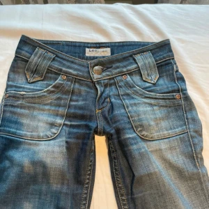 LEE Jeans - Lågmidjade bootcut LEE jeans, i mörkblå färg och med fina detaljerade fickor. Det saknas dock en knapp vid ena bakfickan, men är annars i överlag i väldigt bra skick. Skulle säga att de sitter som en XS i storlek. Säljer pga att de är för små för just mig💕                                                                Innerbenslägnd: Ca 71 cm               Midjemått: Ca 35 cm