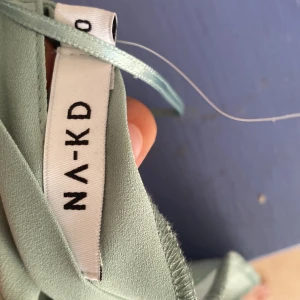 Mintgrön omlottblus från NA-KD - Superfin mintgrön omlottblus från NA-KD med långa trumpetärmar och v-ringning. Blusen har knytband framtill och är gjord i ett lätt, flowy material som känns luftigt och fräscht. Perfekt för dig som gillar en romantisk och trendig look.