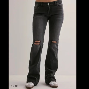 Svarta bootcut jeans med slitningar - Snygga svarta bootcut jeans med slitna detaljer över knäna. Jeansen är från Nelly och dem har blivit lite slitna längst ner vid fötterna då jag trampat ner dem lite. Modellen är bootcut med låg midja 