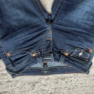 Mörkblå bootcut jeans från true religion  - Snygga mörkblå lågmidjade bootcut jeans från True Religion. Dom är knappt använda.