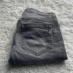 Dondup  - Snygga grå jeans från George i skinny fit-modell. Jeansen har klassisk femficksdesign, silverfärgad D-detalj på bakfickan och röda sömmar vid linningen. Tillverkade i mjukt jeanstyg som sitter tajt och bekvämt.