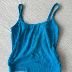Blå ribbad linnetopp från SHEIN - Säljer en blå ribbad linnetopp från SHEIN i storlek XS. Toppen har smala axelband och är tillverkad i ett stretchigt material som sitter snyggt på kroppen. Perfekt att styla med jeans eller kjol för en fräsch look.