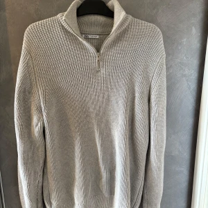 Grå stickad half zip-tröja från Zara - Snygg grå stickad tröja från Zara med half zip och hög krage. Tröjan har en chunky struktur, lång ärm och en clean look som passar perfekt till jeans eller dressade byxor. Perfekt för lager-på-lager under kyliga dagar.