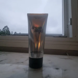 Victoria's Secret Dream Angel bodylotion - Dream Angel bodylotion från Victoria's Secret i en snygg, holografisk silverfärgad tub med svart lock. Ger huden en fräsch doft och silkeslen känsla. Perfekt att ha i väskan eller på sminkbordet för en extra touch av lyx.Har använt den typ 2 gånger så den är inte så använd,den känns helt som ny men bara att jag har använt den 2 gånger🥰