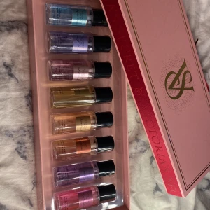 Victoria's Secret parfymset 8-pack - Lyxigt presentset med 8 olika Victoria's Secret body mists i miniflaskor, 75 ml vardera. Parfymerna har färgglada etiketter i blått, lila, rosa, guld och koppar. Kommer i en snygg rosa ask med gulddetaljer och VS-logga. Perfekt för dig som vill testa flera dofter.