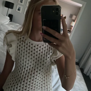 Vit stickad blus med volangärmar Zara - Supersöt vit stickad blus från Zara med hålmönster och breda volangärmar. Toppen är ärmlös och har en luftig, boxig passform som känns både trendig och chill. Perfekt att styla med jeans eller kjol för en fräsch look.🤍