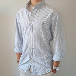 Ralph Lauren Skjorta - Stl L, Slim Fit - Hej säljer en fin Ralph Lauren skjorta i randigt mönster med färgerna ljusblå och vit, Perfekt till sommaren! 🏖🏝 |Skick: 8,5/10, finns 2 små nästan osynliga fläckar | Stl: L, Slim fit | Han på Bilden är 172cm, men skjortan passar längre | Fraktar spårbart med Instabox eller Postnord | Mvh Galgen 🤗