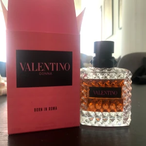 Valentino Donna Born In Roma parfym - Exklusiv parfym från Valentino, Donna Born In Roma. Flaskan är lyxigt designad i genomskinligt glas med nitar och svart kork. Doften kommer i en snygg rosa kartong med svarta detaljer. Perfekt för dig som vill ha en ikonisk och modern doftupplevelse.