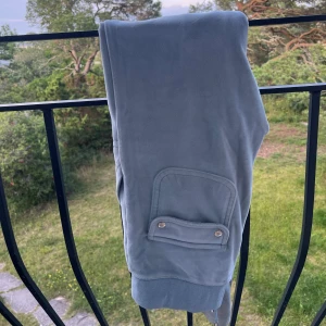 Blå mjukisbyxor Juicy Couture XS - Säljer ett par ljusblå mjukisbyxor från Juicy Couture i storlek XS. Bykorns är ganska my met använda men fortfarande i bra skick. Byxorna har bred resår och snörning i midjan, stora fickor fram och en mjuk, skön känsla. Perfekta för chill dagar eller när du vill vara extra bekväm.