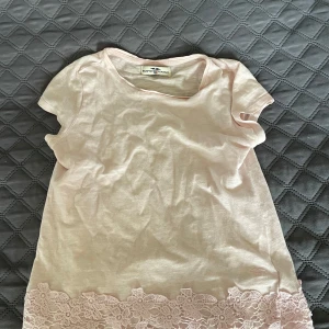 Ljusrosa topp med spetskant - Supersöt ljusrosa topp från Banana Republic med korta ärmar och rund halsringning. Nedtill finns en bred, dekorativ spetskant.