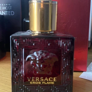 Versace Eros Flame parfym 25ml - Versace Eros Flame parfym i en lyxig röd glasflaska med guldigt lock och ikonisk Medusa-detalj framtill. Flaskan har en fyrkantig form och levereras med matchande röd kartong med gulddetaljer. En doft som sticker ut och känns exklusiv. Det är runt 25ml kvar.