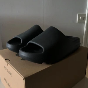 Yeezy Slide  - Adidas Yeezy Slide i modellen Onyx. Helt nya/aldrig använda. Kommer med låda och tags. Storlek 46 men sitter mindre, passar 44-45