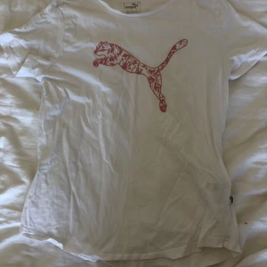 Vit Puma t-shirt - Vit t-shirt från Puma i bomull med klassisk rosa Puma-logga på bröstet. Det står den är storlek L men sitter som en M (enligt mig). Använd 2-3 gånger så den ser ny ut. 