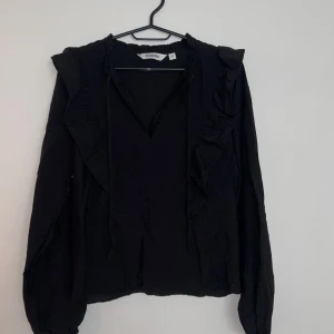 Blus - Svart fin blus med volanger på bröstet. Blusen är från Kappahl och har endast används ett fåtal gånger. Materialet är tunnt men inte genomskinligt. Väldigt populär blus