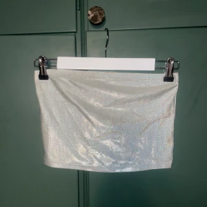 Glittrig silver axelbandslös topp från H&M Divided - Supersnygg glittrig silverfärgad axelbandslös topp från H&M Divided. Perfekt för dig som vill ha en statement piece till din outfit. Använd 1 gång.