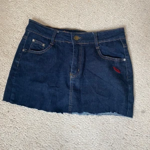 Mörkblå jeanskjol med broderi - Snygg mörkblå jeanskjol med rå kant och broderade röda läppar på både fram- och bakficka💗Skriv innan du klickar på köp eller om du har någon fråga💗