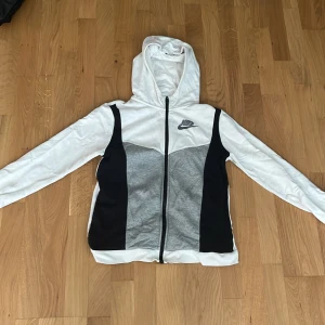 Nike zip hoodie vit/grå - Tjena, säljer min Nike zip hoodie som är andvänd ett fåtal gånger. Jag säljer den eftersom att den inte passar längre och att jag behöver pengarna. Den är riktigt skön och har ett nice material att ha på sig. Den passar dig som är mellan 158-175 centimeter!