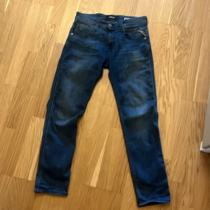 Replay Anbass blå jeans slim fit - Snygga Replay Anbass jeans i blå tvätt med slim fit. Klassisk femficksmodell med dragkedjegylf och diskreta slitningar för en cool look. Jeansen har raka ben och är tillverkade i mjukt bomullsmaterial med stretch för extra komfort.